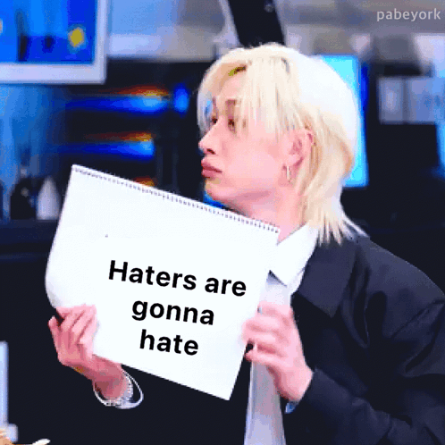 Man in Suit Holding Paper Says Haters Are Gonna Hate