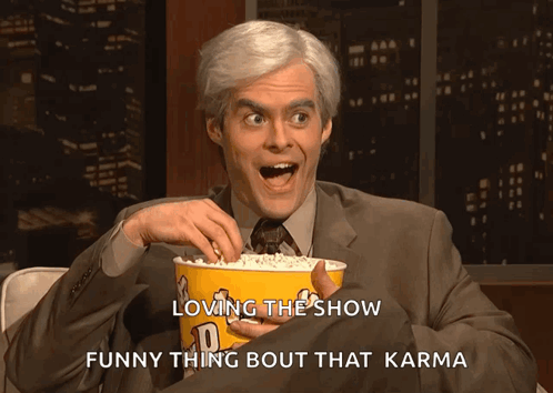Man in Suit Holding Popcorn Says Loving the Show Funny Thing Bout That Karma