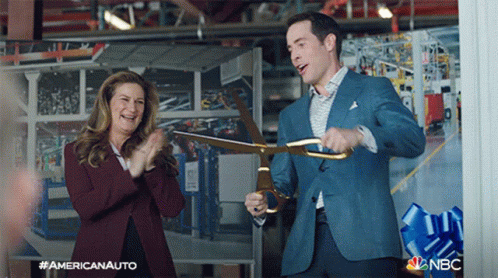 Man in Suit Holding Scissors in Front of Clapping Woman