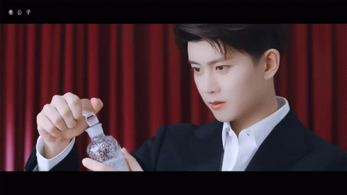 Man in Suit Holding Small Bottle