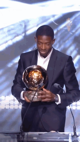 Man in Suit Holding Soccer Ball at Microphone