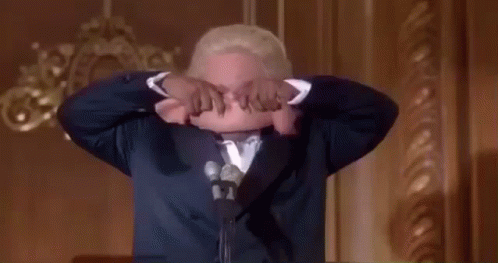 Man in Suit Holds Cloth Over Head Speaking into Mic
