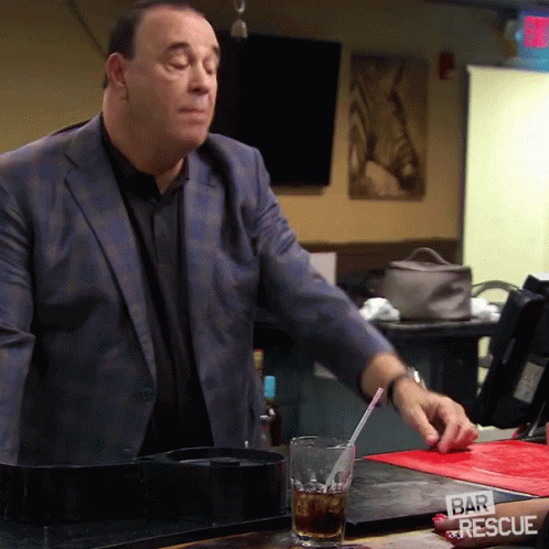 Man in Suit Holds Straw Over Glass Saying Bar and Rescue