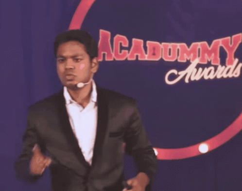 Man In Suit In Front Of Dummy Awards Sign GIF