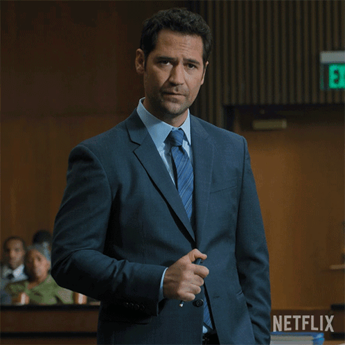 Man In Suit In Front Of Netflix Logo GIF