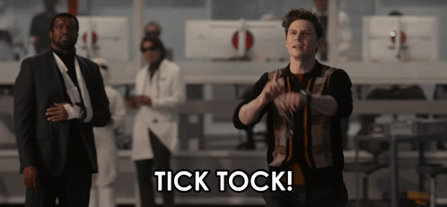 Man in Suit in Front of Tick Tock Sign