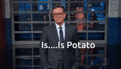 Man in Suit in Front of Wall Saying Is Potato