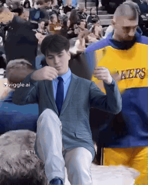 Man in Suit Kneeling Next to Lakers Jersey