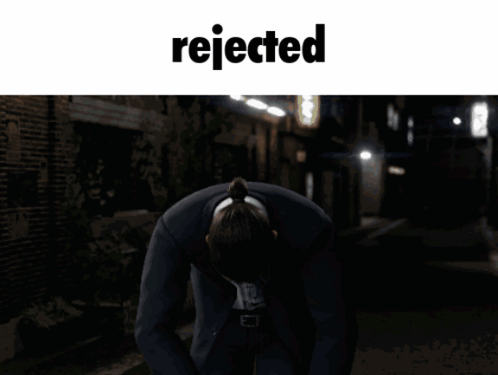 Man in Suit Kneeling With Word Rejected