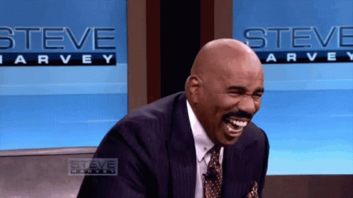 Man In Suit Laughing In Front Of Steve Harvey Sign GIF