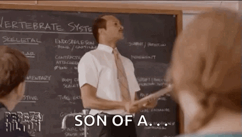 Man in Suit Lecturing to Students by Chalkboard