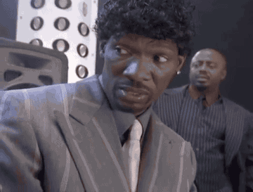 Man in Suit Looking at Camera With Another Man Behind