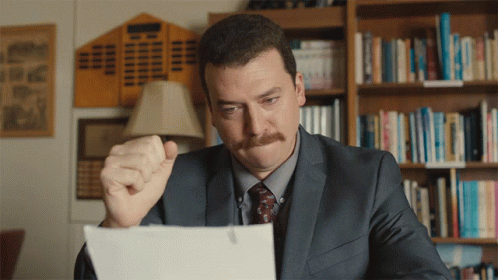 Man in Suit Looking at Paper With Fist in Air