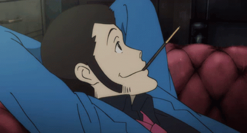 Man In Suit Lying On Couch Eating Stick GIF