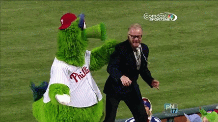 Man in Suit Next to Green Phillies Mascot