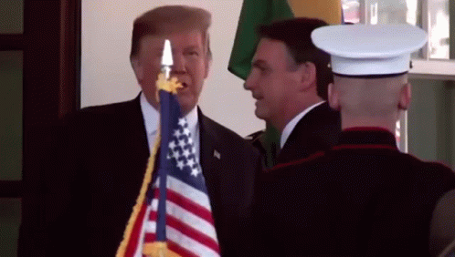 Man in Suit Next to Man in Uniform Holding American Flag