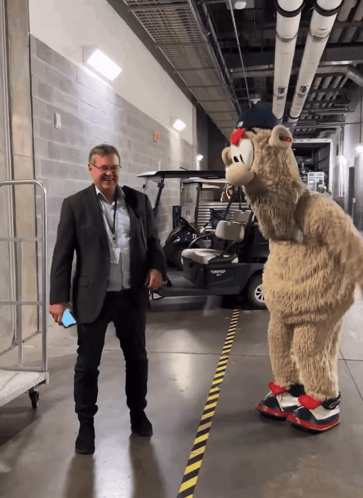Man in Suit Next to Mascot