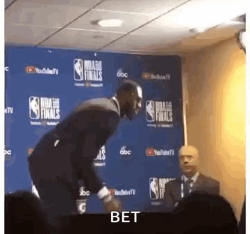Man In Suit Next To NBA Finals Sign GIF