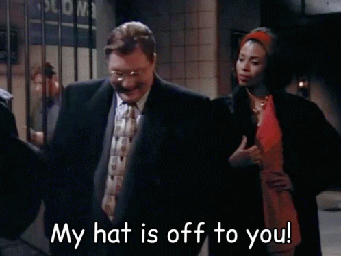 Man In Suit Next To Woman In Red Dress Saying My Hat Is Off To You GIF