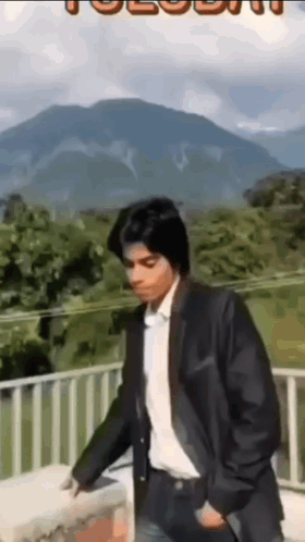 Man In Suit On Balcony With Mountains GIF