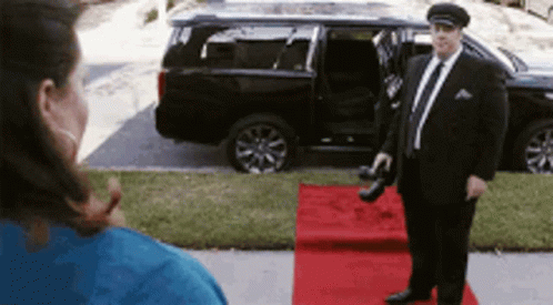 Man in Suit on Red Carpet in Front of Car