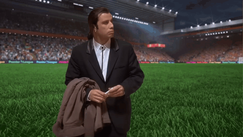 Man in Suit on Soccer Field with Premier League Banner