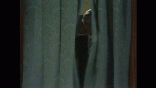 Man in Suit Peeking Through Curtain