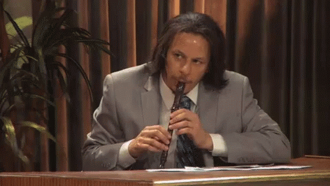 Man In Suit Playing Flute At Desk GIF