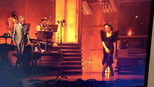 Man in Suit Playing Piano Woman in Black Dress Dancing
