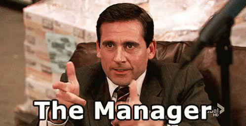 Man In Suit Pointing At Camera Saying The Manager