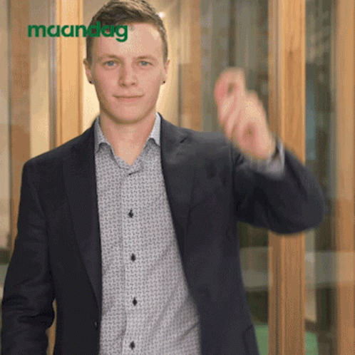 Man in Suit Pointing at Maandag Sign
