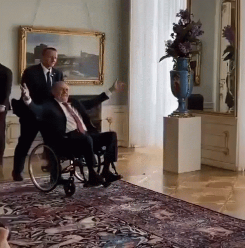 Man In Suit Pushing Man In Wheelchair GIF