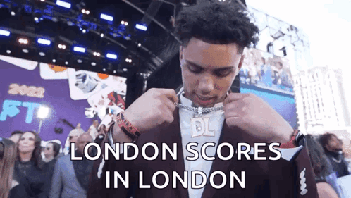Man in Suit Putting on Chain London Scores