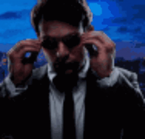 Man in Suit Putting on Sunglasses