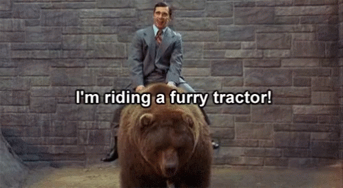 Man in Suit Riding Furry Tractor on Bear