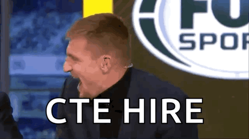 Man in Suit Says CTE Hire in Front of Soccer Logo