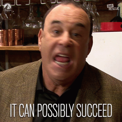 Man in Suit Says It Can Possibly Succeed in Front of Bar Rescue Sign
