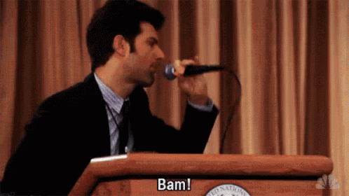 Man In Suit Singing Into Microphone At Podium GIF