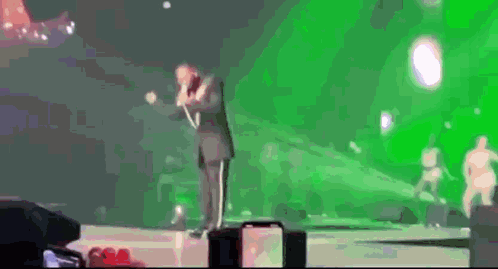 Man in Suit Singing Into Microphone on Stage