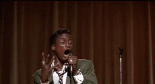 Man in Suit Singing Into Microphone on Stage