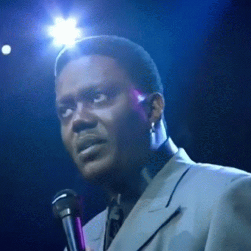 Man in Suit Singing Into Microphone on Stage