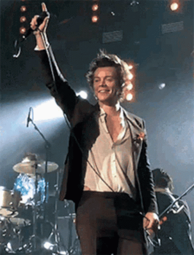 Man in Suit Singing Into Microphone on Stage With Drum Set