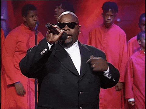 Man in Suit Singing Into Microphone With Choir