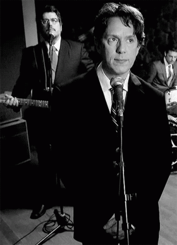 Man In Suit Singing Into Microphone With Guitarist GIF