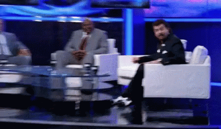 Man in Suit Sits on TV Set