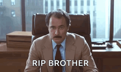 Man in Suit Sitting at Desk Rip Brother
