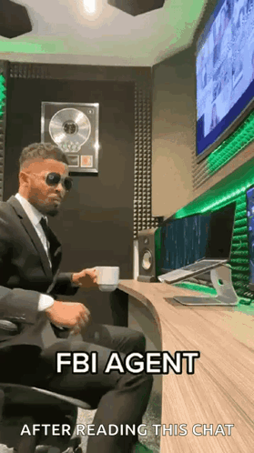 Man In Suit Sitting At Desk With Coffee And Sunglasses GIF