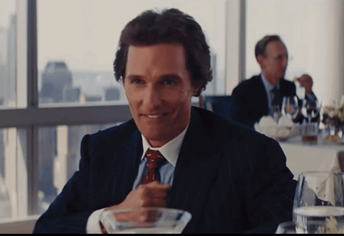 Man in Suit Sitting at Table With Martini
