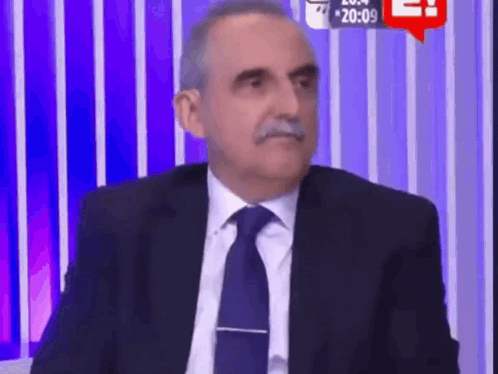 Man in Suit Sitting Before Purple Striped Wall