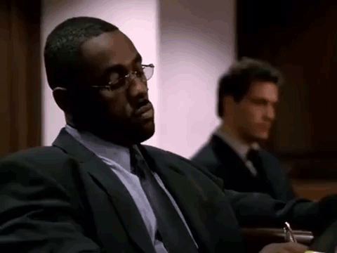 Man in Suit Sitting in Courtroom With Another Man